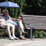 old couple sitting on the bench with umberllA