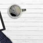 a man is drawing arrow in the tablet with a cup of coffee